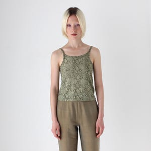 Może przedstawiać: Kobieta w zielono-brązowej koszulce na ramiączkach z nadrukiem skóry węża i pasujących brązowych spodniach.