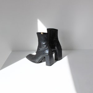 May include: A pair of black leather ankle boots with a square toe and a chunky block heel.