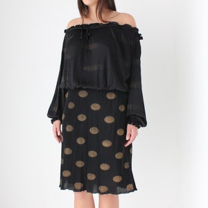 May include: A black off-the-shoulder top with long sleeves and a gathered waist, paired with a black skirt with gold polka dots.