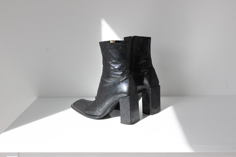 May include: A pair of black ankle boots with a chunky heel and a glittery finish.