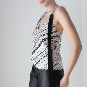 May include: A white halter top with a black and white abstract print. The top has a long black tie that hangs down the front.