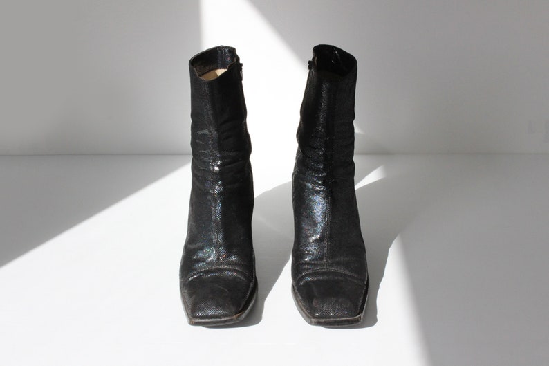 May include: A pair of black ankle boots with a sparkly finish. The boots have a square toe and a low heel.