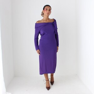 May include: A purple off-the-shoulder dress with long sleeves and a bow detail at the neckline.