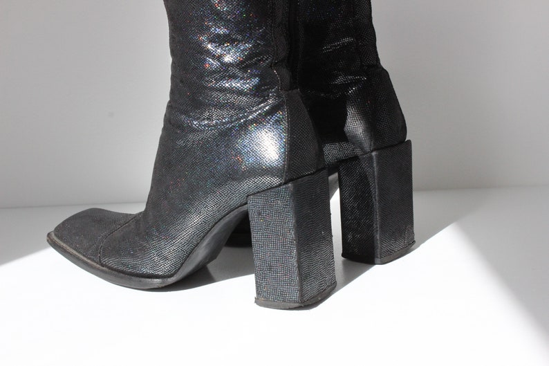 May include: A pair of black sparkly heeled boots with square toes and block heels.