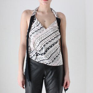 May include: A white halter top with a black and white wavy pattern. The top has long black straps that tie at the neck.