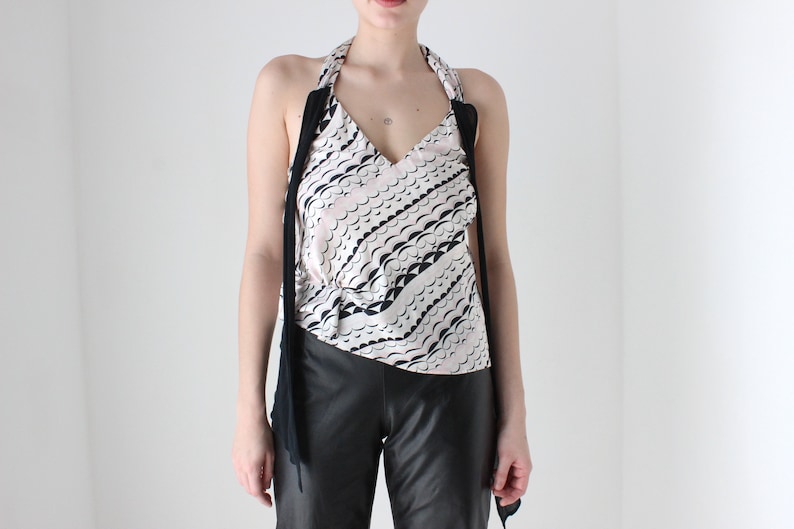 May include: A white halter top with a black and white wavy pattern. The top has long black straps that tie at the neck.