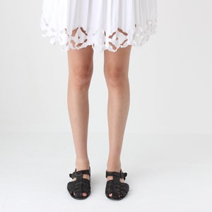 May include: A pair of black leather sandals with a woven design. The sandals have a strap across the foot and an ankle strap.