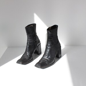 May include: A pair of black ankle boots with a square toe and a chunky block heel.