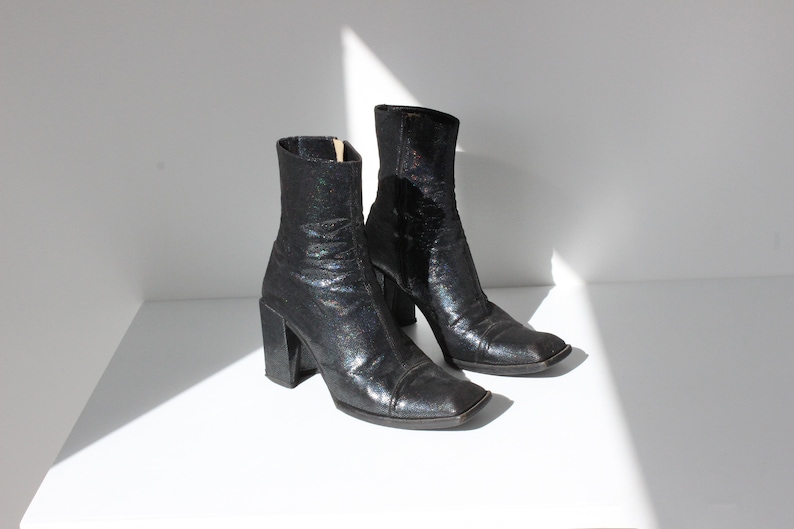 May include: Pair of black ankle boots with a square toe and chunky heel. The boots have a glittery finish.