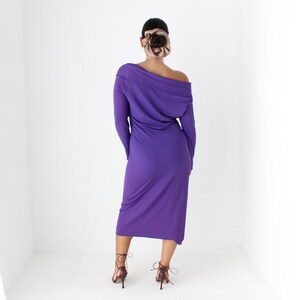 May include: A long-sleeved, purple dress with a cowl neck and a slightly asymmetrical hemline. The dress is made of a soft, stretchy fabric.