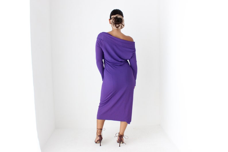 May include: A long-sleeved, purple dress with a cowl neck and a slightly asymmetrical hemline. The dress is made of a soft, stretchy fabric.