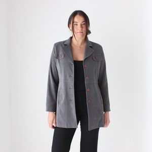 May include: A gray corduroy jacket with a collared neckline, long sleeves, and a button closure. The jacket has two flap pockets on the front and a brown button detail.