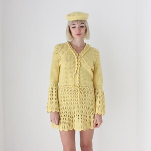 May include: A yellow crochet dress with bell sleeves and a crocheted hat.