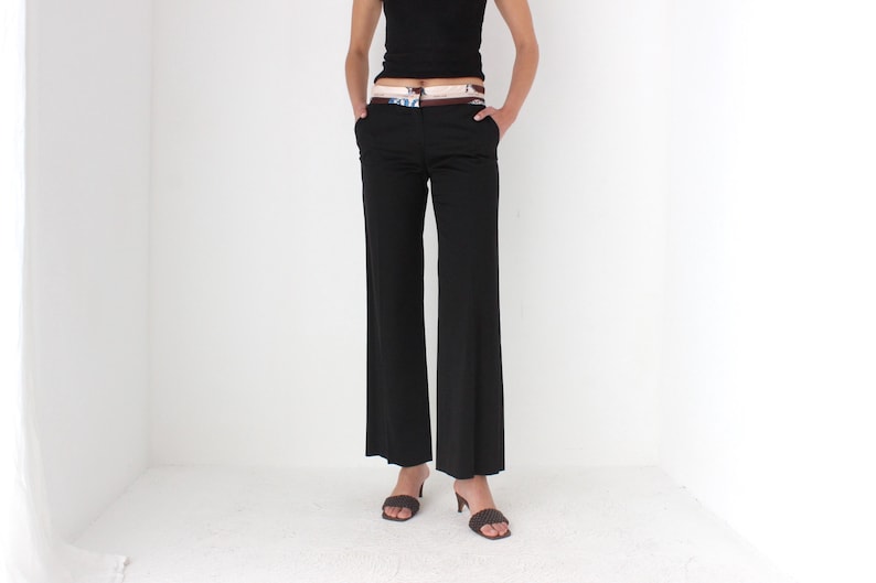 May include: Black wide-leg pants with a brown belt and a patterned fabric insert. The pants are worn by a person with bare arms and feet.