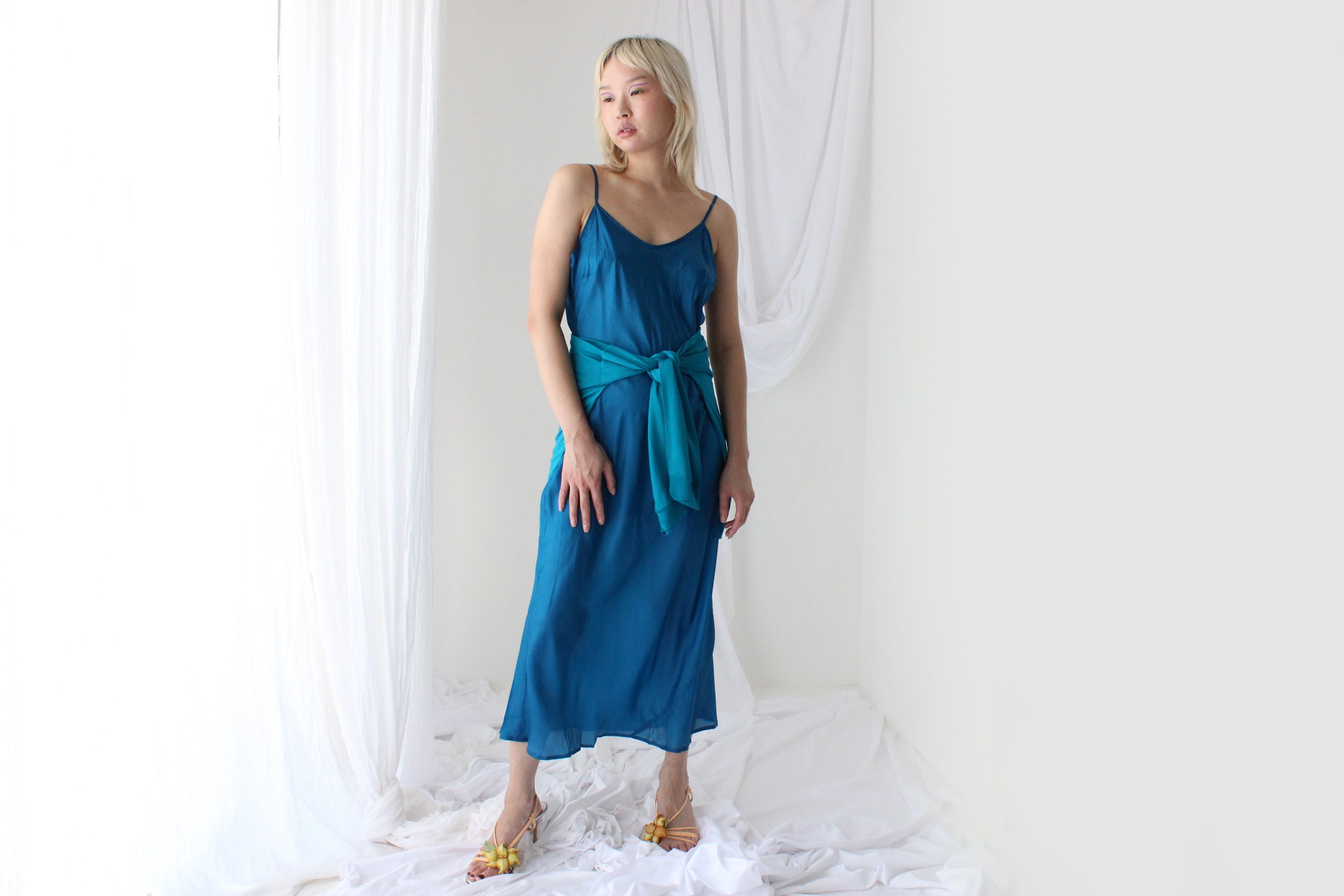 women teal dress on the bias designs The Cloud Nine Dress embodies elegance with its luxurious rayon silk fabric  and exclusive SACHA DRAKE print. The bias-cut A-line silhouette flows  effortlessly, complemented by a V-neck and