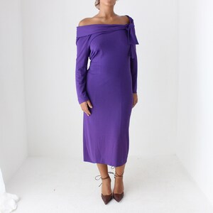May include: A long-sleeved, purple off-the-shoulder dress with a bow detail at the neckline.
