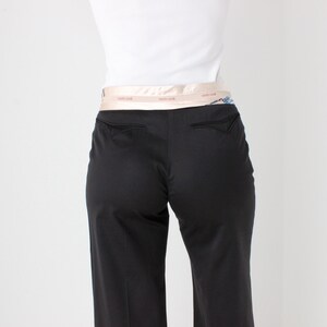 May include: Black pants with a wide leg and a light pink satin belt.