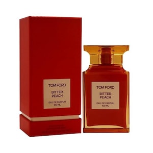 May include: A perfume bottle and box set. The bottle is a rectangular shape with a clear top and filled with a reddish-orange liquid. The box is a solid red color. Both the bottle and box have the text "TOM FORD BITTER PEACH EAU DE PARFUM 100 ML".