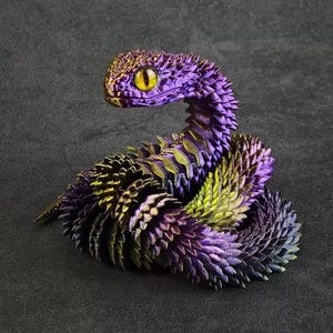 May include: A coiled snake figurine featuring a highly textured, iridescent scale pattern that shifts between deep purple, metallic gold, and dark green hues. The snake has a prominent, alert head with a single, large, bright yellow eye with a black pupil.