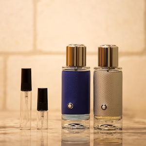 May include: Two perfume bottles with silver caps and a blue and silver textured body, plus two small sample spray bottles. The bottles are on a reflective surface.