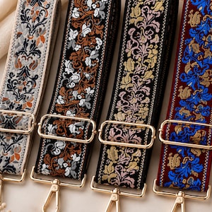 May include: Four adjustable bag straps featuring intricate floral embroidery in distinct color palettes: light gray, dark brown, black with gold, and deep red with blue. Each strap includes polished gold-tone metal hardware, sliders, and swivel clasps.