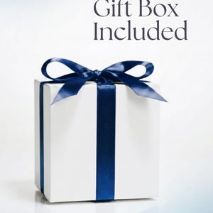 Pode incluir: Uma caixa de presente branca com uma fita e la&ccedil;o azul marinho. O texto "Gift Box Included" est&aacute; no topo. O texto "HANDWRITTEN CARDS CAN BE INCLUDED UPON REQUEST" est&aacute; na parte inferior.