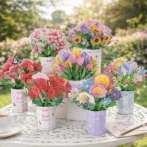 Puede incluir: Una colección de coloridos ramos de flores de papel en varios jarrones, dispuestos sobre una mesa blanca. Los ramos presentan una variedad de flores, como tulipanes, girasoles y margaritas. Algunos jarrones tienen el texto "Best Wishes" y "Hello Sunshine".