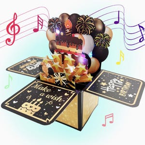 May include: A pop-up birthday card featuring a chocolate cake, balloons, and star decorations. The card is black and gold with the phrases "Make a wish" and "Happy Birthday". Musical notes are in the background.