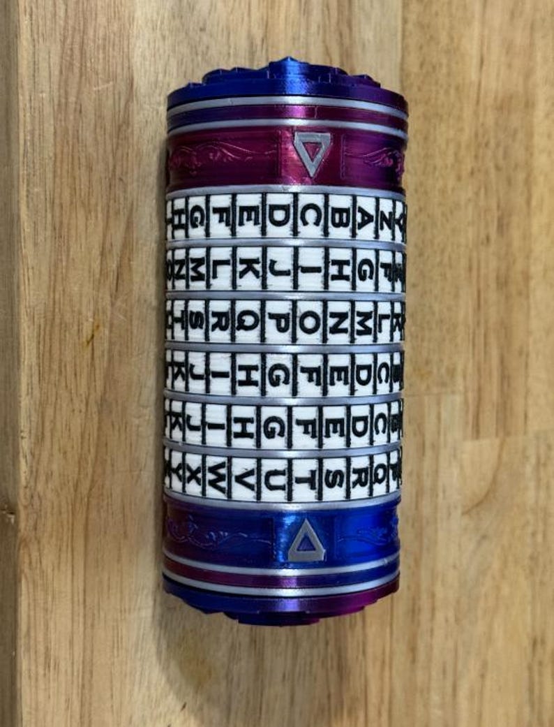May include: A cylindrical puzzle with rotating lettered rings. The top and bottom sections are blue, with a magenta band in the middle. The rings are white with black letters. A triangle is visible on the magenta band.