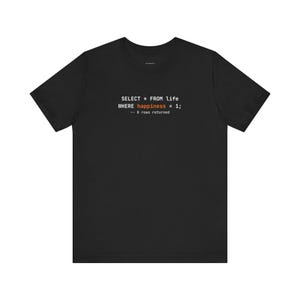 Puede incluir: Camiseta negra con texto blanco y naranja. El texto dice "SELECT * FROM life WHERE happiness = 1; -- 0 rows returned". La camiseta es de manga corta y cuello redondo.