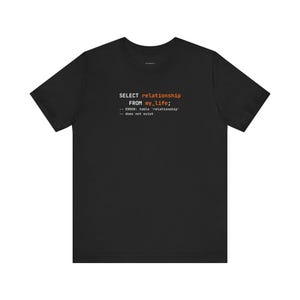 Może przedstawiać: Czarny t-shirt z napisem "SELECT relationship FROM my_life; -- ERROR: table 'relationship' -- does not exist" w kolorze białym i pomarańczowym. Okrągły dekolt.