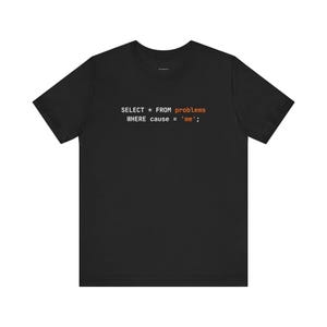 Może przedstawiać: Czarny t-shirt z napisem "SELECT * FROM problems WHERE cause = 'me';" w kolorze białym i pomarańczowym. Codzienna odzież, odpowiednia do codziennego użytku.