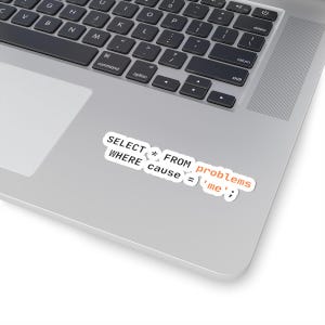 Könnte beinhalten: Ein weißer Aufkleber mit schwarzem Text, der "SELECT * FROM problems WHERE cause = 'me';" lautet, ist auf einem Laptop platziert. Der Text ist in einem Programmiersprachenformat, mit einigen Wörtern in Orange.