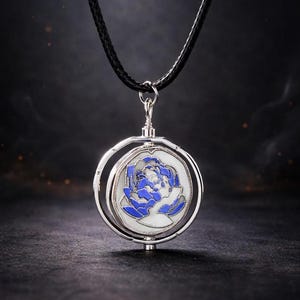 May include: A silver-toned pendant necklace featuring a blue and white floral design. The pendant is circular, with a rotating outer ring. The necklace has a black cord. The background is dark.