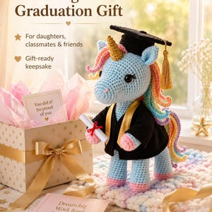 May include: A crocheted unicorn wearing a graduation cap and gown, holding a diploma. The unicorn has a blue body, rainbow mane, and a golden horn. The image includes text that reads "A Magical Graduation Gift". A gift box with a bow and a card that says "Dream big Work hard Shine bright" are also present.