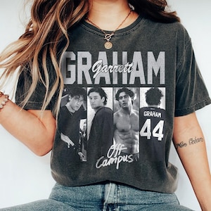 May include: A charcoal gray short-sleeve t-shirt featuring a vintage-style graphic print. The design includes the text GRAHAM and Garrett, four black and white photographic panels of a man, and the text Off Campus with the number 44 on a jersey.