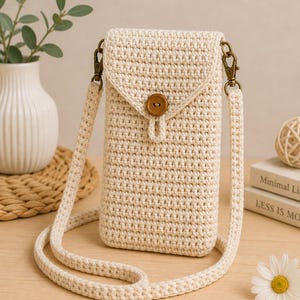 Può includere: Borsa a tracolla all'uncinetto color crema con chiusura a patta e bottone in legno. La borsa presenta una lunga tracolla regolabile e hardware color bronzo. Un accessorio elegante per trasportare un telefono o piccoli oggetti.