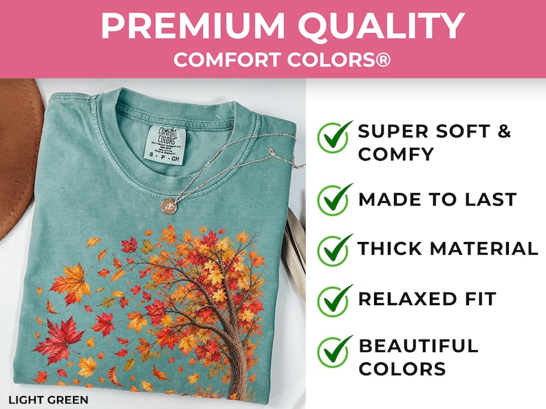May include: A light green Comfort Colors t-shirt featuring a graphic of a tree with orange, red, and yellow autumn leaves blowing in the wind. The shirt includes text stating Premium Quality, Super Soft & Comfy, Made to Last, Thick Material, Relaxed Fit, and Beautiful Colors.