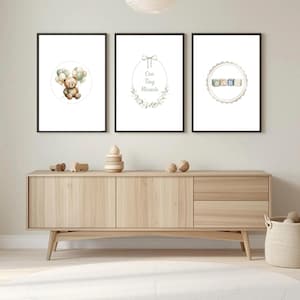 Op de afbeelding: Drie ingelijste kunstprints voor de kinderkamer. De prints tonen een teddybeer met ballonnen, de tekst "Our Tiny Miracle" in een bloemenkrans en blokken met de tekst "BABY". De prints zitten in zwarte lijsten.