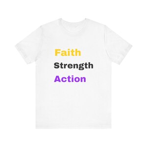 May include: A white short-sleeved t-shirt featuring three lines of text centered on the chest. The word Faith is printed in yellow, Strength is printed in dark gray, and Action is printed in purple, all in a bold, sans-serif font.
