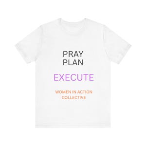 May include: A white short-sleeved t-shirt featuring the black text PRAY PLAN, the purple text EXECUTE, and the orange text WOMEN IN ACTION COLLECTIVE printed on the front. The shirt has a crew neckline and a standard fit with short sleeves.