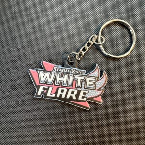 May include: A keychain featuring the text "WHITE FLARE" in white and black, with pink and silver accents. The keychain has a silver chain and ring. The text "SCARLET & VIOLET" is above the main text.
