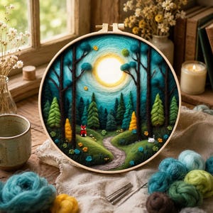 May include: A round embroidery hoop featuring a forest scene with a path, trees, and a bright sun. The artwork is in shades of green, blue, and yellow. A small red fox and white rabbit are visible. The hoop is surrounded by yarn and craft supplies.