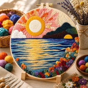 May include: A handcrafted embroidery hoop featuring a sunset over the ocean. The artwork uses various colors of yarn to depict the sun, water, mountains, and flowers. The hoop is displayed on a wooden stand, with additional craft supplies visible.