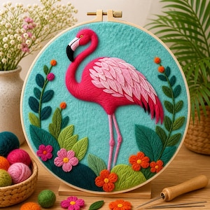 May include: A vibrant, handmade embroidery hoop featuring a pink flamingo with a black beak and legs, set against a turquoise background. The design includes green leaves, orange and pink flowers, and is framed in a wooden hoop. A decorative piece.