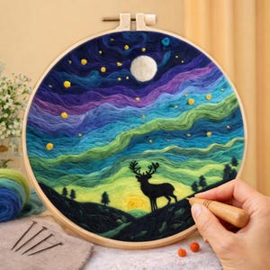 May include: A handmade embroidery hoop displaying a landscape with a deer silhouette, trees, and a colourful sky with a moon and stars. The artwork is set in a wooden hoop, showcasing a fibre art piece.