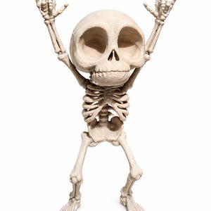 May include: A beige, stylized skeleton figurine with an oversized head and large, hollow eye sockets. The figure stands with both arms raised above its head, with fingers positioned in a rock-and-roll hand gesture. The surface has a textured finish.