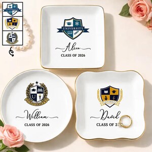 May include: Three white ceramic trinket dishes with gold-toned rims. One square dish features a blue university crest and the text Alice CLASS OF 2026. A round dish shows a gold crest and William CLASS OF 2026. A scalloped dish displays David CLASS OF 2026.