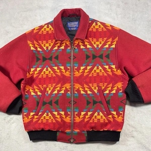 Könnte beinhalten: Rote Jacke mit Reißverschluss und farbenfrohem geometrischen Muster auf der Vorderseite und am Kragen. Die Jacke hat schwarze gerippte Bündchen und Saum. Das Pendleton-Etikett ist am Kragen sichtbar.