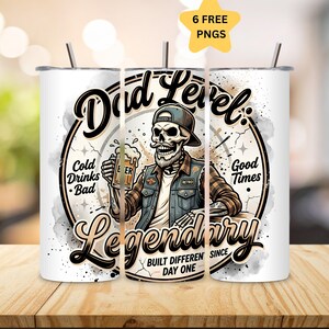 May include: A white cylindrical tumbler with a metal straw featuring a graphic of a skeleton wearing a baseball cap and vest, holding a beer mug. Text includes Dad Level: Legendary, Cold Drinks Bad, Good Times, and Built Different Since Day One.
